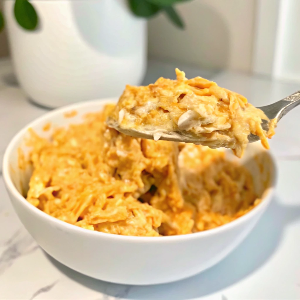 A spoonful of creamy, orange-colored salmon is scooped from a white bowl. The dish consists of slices of salmon and a delicious, spicy mayonnaise-based sauce.