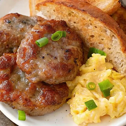 A breakfast of beef breakfast sausage, eggs, and toast served on a white plate with a sprinkling of parsley.