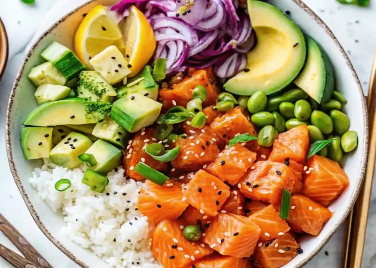 A colorful salmon poke bowl with diced raw salmon, avocado slices, cucumber, edamame, and rice, garnished with sesame seeds and green onions.”