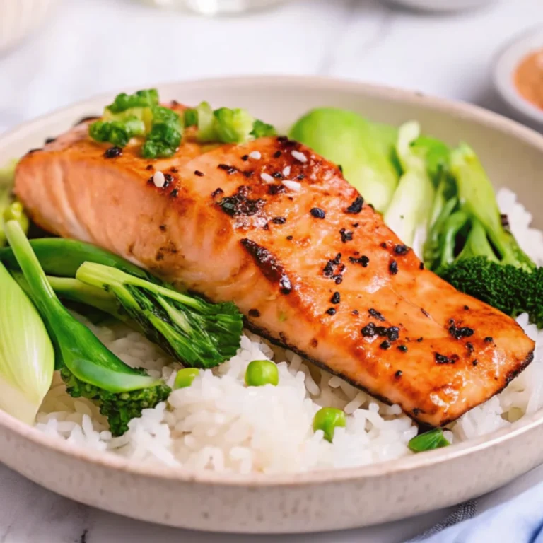 A plated meal featuring a seared Salmon Asian Rub Recipe served over fluffy white rice with peas, accompanied by vibrant steamed bok choy and broccoli, garnished with sesame seeds and herbs.