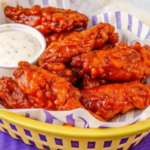 serving plate a Honey Chipotle Chicken Crispers piled high with golden-brown, crispy chicken strips lavishly coated in a thick, sweet, and spicy honey-chipotle glaze