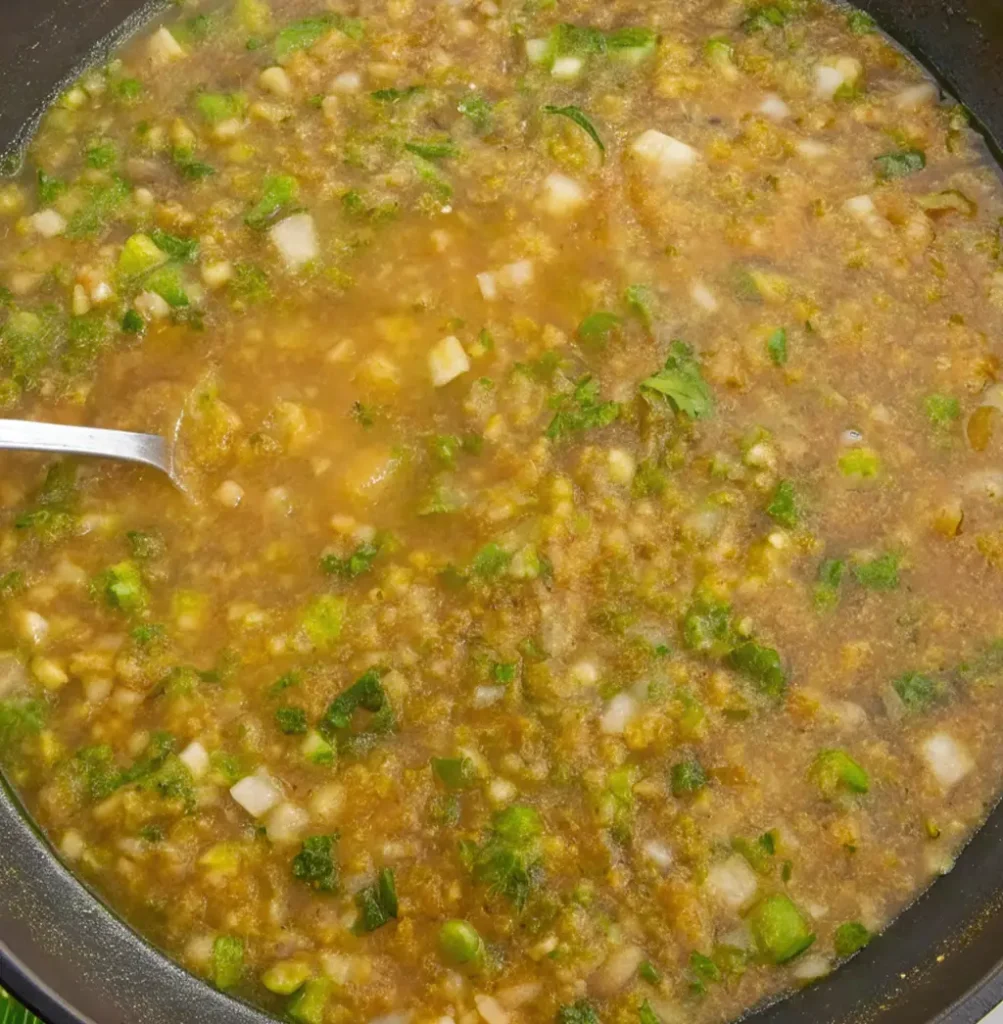 A large frying pan contains a generous amount of ready-made étouffée, a thick, golden brown sauce filled with chopped onions, green peppers, butter, and flour.