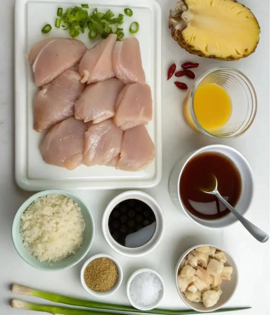 This image shows ingredients for Hawaiian BBQ Chicken Recipe, including raw chicken breasts, chopped scallions, half a pineapple, dried chili peppers, pineapple juice, a dark sauce mixture, cooked rice, soy sauce, spices, salt,