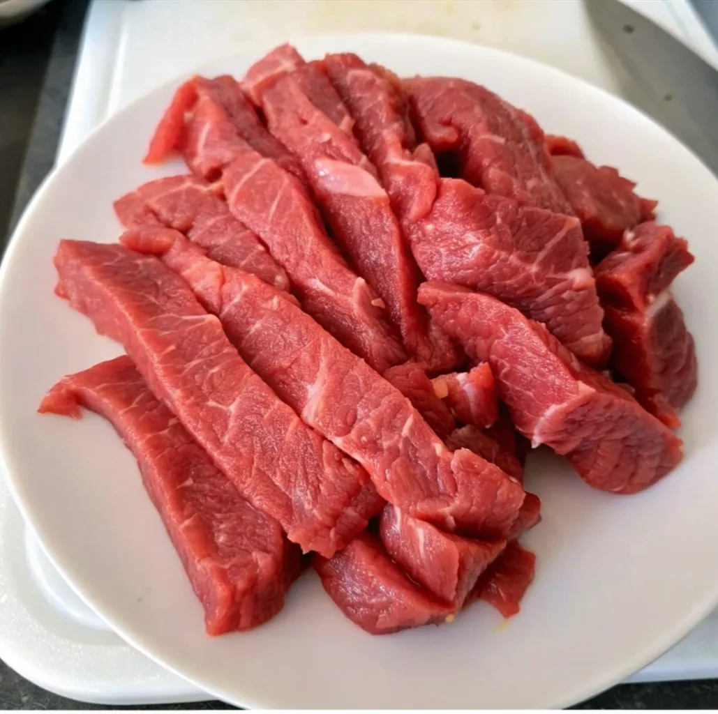 several slices of raw, bright red beef cut into thin strips
