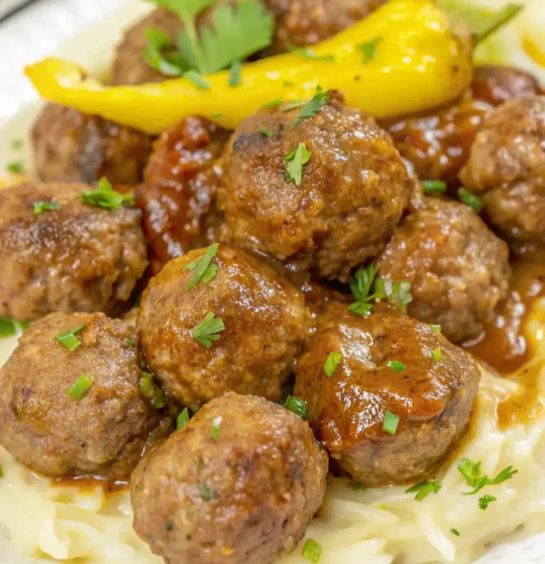 Glazed Mississippi meatballs and peperoncini peppers served on a bed of mashed potatoes, garnished with fresh chopped parsley.