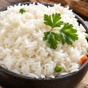 FluffySteam Cooked Rice served in a dark ceramic bowl, garnished with fresh green parsley sprigs, green peas, and diced carrots on a rustic wooden table.