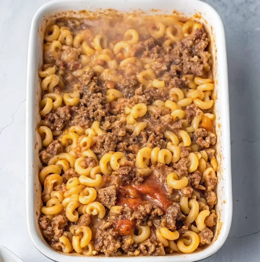 cheesy bacon cheeseburger casserole featuring elbow macaroni, savory ground beef, and crispy bacon bits smothered in a rich, melted cheddar cheese sauce and diced tomatoes.