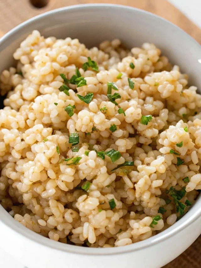 A white bowl filled with cooked Brown rice instant pot is garnished with freshly chopped green herbs, presenting a nutritious and appetizing side dish ready to be enjoyed.