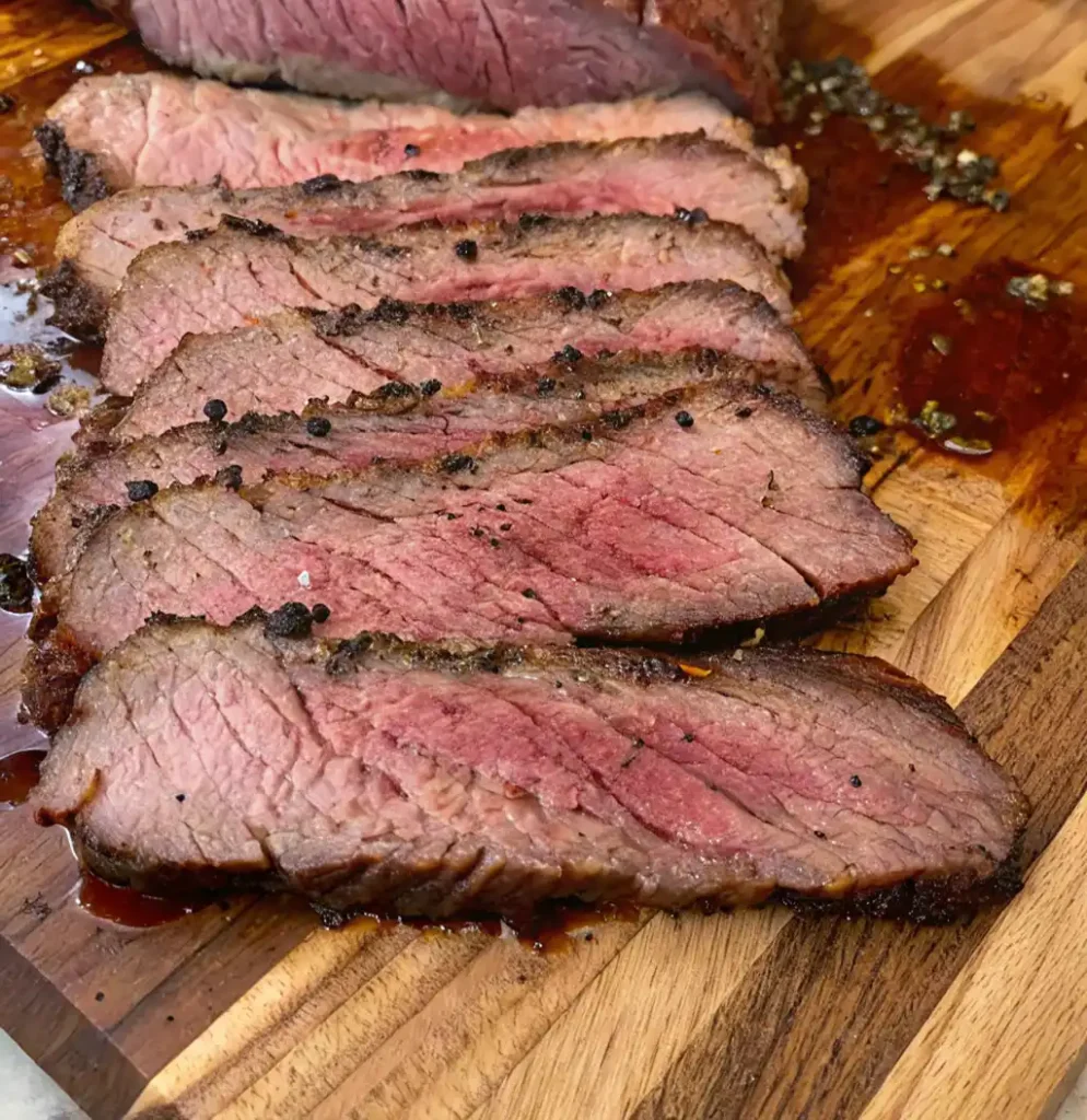 Slices of dry brined brisket rest on a wooden board, showcasing a dark, seasoned crust, tender pink center, and glistening juices. Coarse black pepper and